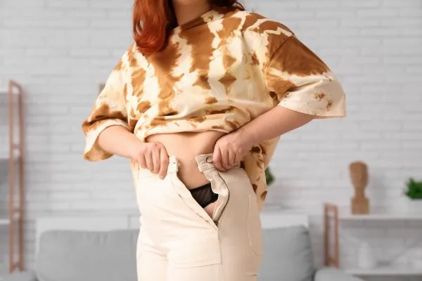 Image of woman trying to do her trousers up after pregnancy weight gain Northfield